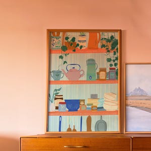 Peut inclure: Une impression encadrée d'une étagère de cuisine avec divers objets. L'œuvre présente une théière rose, une cruche orange et des pots d'épices. De la verdure et du papier peint à rayures bleues et blanches ajoutent à l'esthétique. Le cadre est de couleur marron clair.