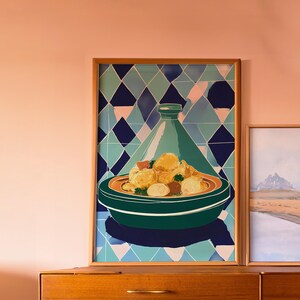 Peut inclure: Une impression encadrée d'un plat de tajine marocain, avec un plat vert et orange rempli de nourriture, surmonté d'un couvercle conique vert. Le fond est un motif géométrique de losanges bleus, verts et roses. Le cadre est en bois.