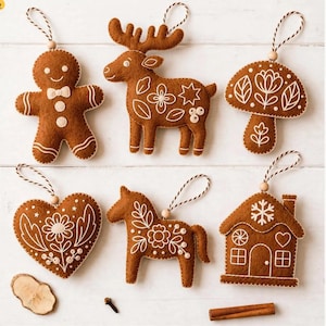 May include: Six brown felt ornaments featuring white embroidered details, including a gingerbread person, a reindeer, a mushroom, a heart, a horse, and a house. Each ornament has a hanging loop with a small wooden bead attached.