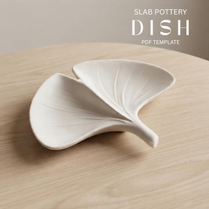 Peut inclure: Un plat en céramique blanche en forme de feuille de ginkgo avec des détails de nervures en relief. Le texte SLAB POTTERY DISH PDF TEMPLATE est visible dans le coin supérieur droit. Le plat présente une finition mate lisse et une forme organique.