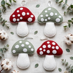 Pode incluir: Quatro enfeites de feltro em forma de cogumelo com caules brancos e chapéus em vermelho ou verde sálvia, cada um com pontos circulares de feltro branco e uma fita branca para pendurar. O conjunto inclui dois cogumelos vermelhos e dois verdes.