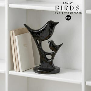 May include: A glossy black ceramic sculpture of two birds perched on a branch, accompanied by a stack of books. The text FAMILY BIRDS POTTERY TEMPLATE PDF is visible in the upper right corner, indicating a digital pattern for this object.