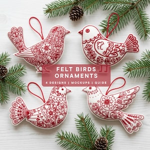 Puede incluir: Cuatro adornos de pájaros de fieltro blanco con diseños florales bordados en rojo y lazos rojos para colgar. Los pájaros están dispuestos alrededor de ramas de hoja perenne y piñas sobre una superficie de madera blanca. Se muestra el texto "FELT BIRDS ORNAMENTS".