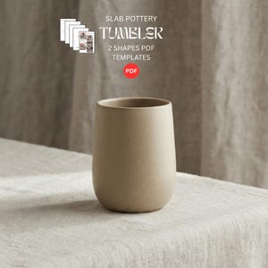 以下が含まれることがあります： 滑らかでマットな質感のベージュ色の陶器製タンブラー。底は丸みを帯びています。タンブラーの上部には「SLAB POTTERY TUMBLER 2 SHAPES PDF TEMPLATES」というテキストと赤いPDFアイコンが表示されています。シンプルでニュートラルなプレゼンテーションです。