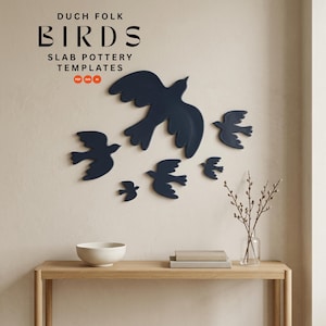 Puede incluir: Decoración mural con forma de pájaros azul marino de varios tamaños, dispuestos en formación de bandada. El texto "DUCH FOLK BIRDS SLAB POTTERY TEMPLATES" es visible. Montado sobre una pared beige claro.
