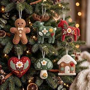 May include: Six felt ornaments hanging from branches, including a brown gingerbread person, a green reindeer, a red horse, a red heart, a green mushroom, and a tan house, all featuring intricate floral embroidery and white hanging strings.