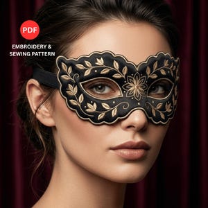 Può includere: Una maschera da ballo nera con intricati ricami floreali dorati e un bordo smerlato. La maschera include un cinturino elastico nero ed è presentata come un modello di cucito e ricamo in PDF. Il design mostra motivi a foglie e fiori simmetrici.