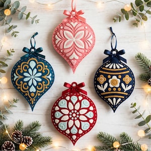 May include: Four teardrop-shaped felt ornaments featuring intricate layered patterns in pink, teal, dark blue, and red. Each ornament is topped with a matching satin ribbon bow and a hanging loop, showcasing detailed embroidery and cut-out designs.