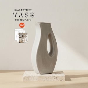 May include: A gray ceramic vase with a unique, open design. The vase has a smooth, curved shape with a large, oval opening. The text "SLAB POTTERY VASE PDF TEMPLATE" is displayed above the vase. The vase is on a square, textured base.
