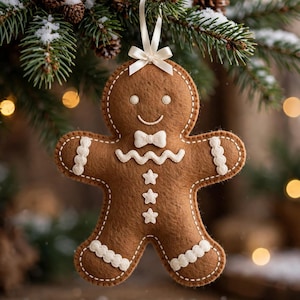 Op de afbeelding: Een bruine vilten peperkoekman-ornament met witte stiksels, een kleine witte vlinderdas, drie witte stervormige knopen en witte geschulpte randen op de armen en benen. Aan de bovenkant zit een crèmekleurig lintje om op te hangen.