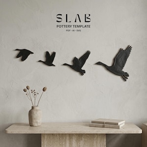 May include: A wall-mounted art piece featuring four black geese in flight. The geese are arranged in a sequence, creating a sense of movement. The word "SLAB" is displayed above the geese, with "POTTERY TEMPLATE" and "PDF - AI - SVG" below it.