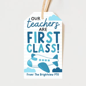 Peut inclure: Une étiquette cadeau blanche avec une illustration d'avion bleu et blanc et le texte "Our teachers are FIRST CLASS!" en bleu. L'étiquette comprend le texte "From: The Brightview PTO" et une ficelle beige.