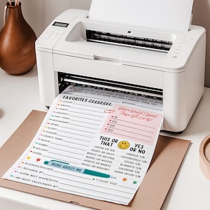 May include: A white printer printing a colorful questionnaire with prompts like "Favorites," "This or That," and "Where Would I Spend These Gift Cards?" A brown envelope is under the printed sheet.