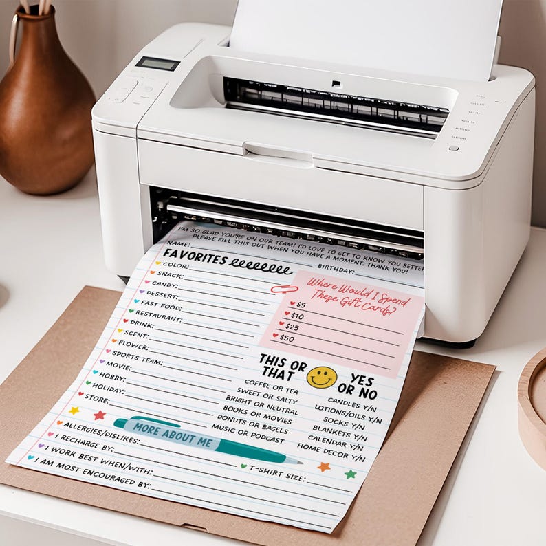 May include: A white printer printing a colorful questionnaire with prompts like "Favorites," "This or That," and "Where Would I Spend These Gift Cards?" A brown envelope is under the printed sheet.