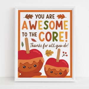 Puede incluir: Una impresión enmarcada con dos manzanas de caramelo de dibujos animados con caras sonrientes. El texto dice YOU ARE AWESOME TO THE CORE! Thanks for all you do! El diseño incluye hojas de otoño y bayas en colores naranja, marrón, rojo y verde.