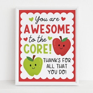 May include: A framed print with a white border features the text "You are AWESOME to the CORE!" in red and green. Two smiling apple illustrations are included. The phrase "THANKS FOR ALL THAT YOU DO!" is also present.