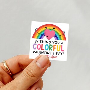 May include: A square sticker with a rainbow design holding a pink heart. The text reads "Wishing You a Colorful Valentine's Day!" with the name "Madison" below. The rainbow has a smiling face.