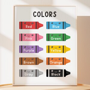 May include: A framed educational poster with the word "COLORS" at the top. Below, cartoon crayons in red, blue, pink, green, purple, yellow, brown, orange, gray, and black are displayed, each labeled with its color name.