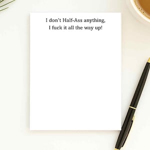 May include: A white notepad with the text "I don't Half-Ass anything, I fuck it all the way up!" is next to a black pen with gold accents. A cup of coffee sits in the upper right corner.