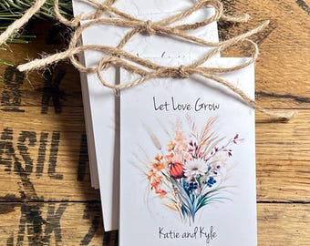 Può includere: Buste di semi bianche legate con spago, con un design floreale e la scritta "Let love Grow". Le buste sono personalizzate con i nomi "Katie and Kyle" e la data "09.13.2025."