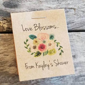 Pu&ograve; includere: Un biglietto marrone con il testo "Love Blossoms... From Kayley's Shower" e un'illustrazione floreale con fiori rosa, gialli e verdi.