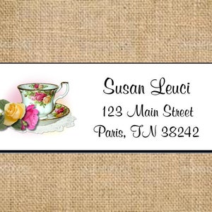 May include: A white teacup with floral designs and a saucer with a lace doily. The teacup is filled with a pink and yellow floral arrangement. The text on the label reads "Susan Leuci, 123 Main Street, Paris, TN 38242".