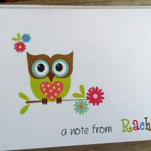 May include: A white notebook with a colorful owl illustration. The owl has a green body, brown head, and a pink heart. The text "a note from Rachel" is written in colorful letters.