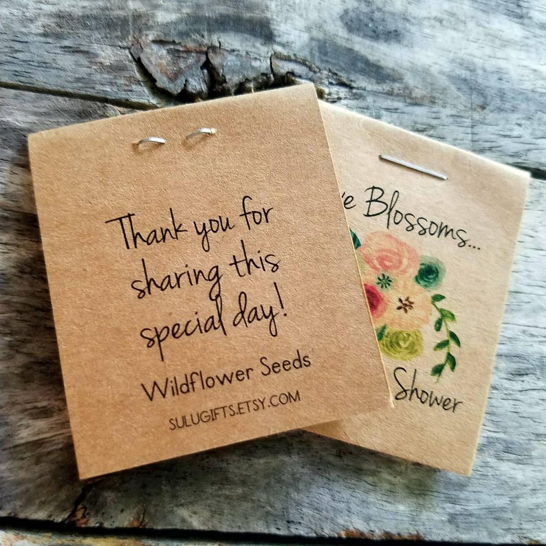 Pu&ograve; includere: Due pacchetti di carta marrone con testo bianco. Il primo pacchetto dice "Thank you for sharing this special day! Wildflower Seeds SULUGIFTS.ETSY.COM". Il secondo pacchetto dice "e Blossoms... Shower".