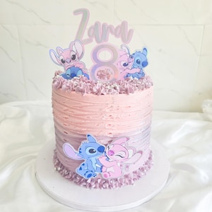 Può includere: Una torta rotonda a più strati con glassa rosa e viola. La torta è decorata con ritagli di personaggi dei cartoni animati, il nome "Zara" e il numero "8". La torta è su un supporto bianco.