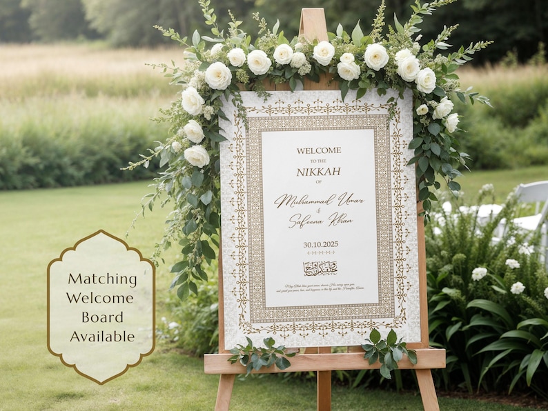 May include: A wedding welcome sign on a wooden easel, adorned with white roses and greenery. The sign features ornate gold detailing and the words "Welcome to the Nikkah" followed by names and a date. A matching welcome board is available.