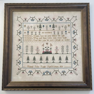 May include: Framed cross-stitch sampler with a brown wooden frame. The sampler features floral and tree motifs, with text that reads "MY MOTHER" and a verse. The text also includes the name "Hannah Judes Knight Aged 8 years 1826".