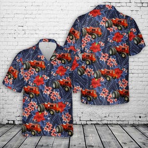 Puede incluir: Dos camisas de manga corta con botones y fondo azul marino. Las camisas presentan un estampado repetido de tractores naranjas, flores de hibisco rojas y hojas azules. Las camisas están hechas de una tela ligera.