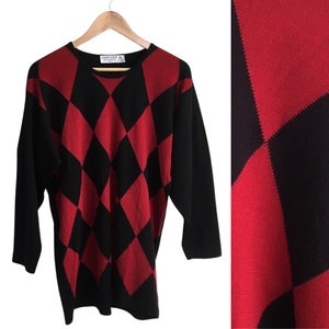 May include: Red and black diamond patterned sweater with a crew neck and long sleeves. The sweater has the label "Jaeger" on the front.
