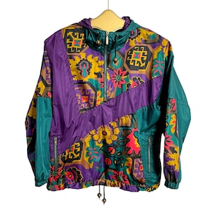 May include: A colorful, patterned jacket with a purple, teal, and brown color scheme. The jacket has a zipper closure and a drawstring at the bottom.