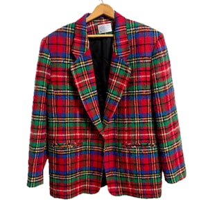 May include: A vintage plaid blazer in red, green, blue, and yellow. The jacket features a classic notched collar, two front pockets, and a black lining. The blazer is hanging on a wooden hanger.