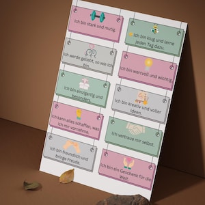 Könnte beinhalten: Ein Motivationsposter mit Affirmationen auf Deutsch. Das Poster zeigt rechteckige Karten mit Sätzen wie "Ich bin stark und mutig" und "Ich werde geliebt, so wie ich bin". Die Karten sind in Rosa, Grün und Grau gehalten.