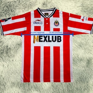 May include: Red and white striped soccer jersey with the word "MEXLUB" in gold letters. The jersey has a white collar and the "Atletica" logo. The sleeves are red and white striped with black trim. The sleeve length is approximately 22.83 inches.