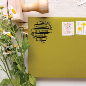 Könnte beinhalten: Ein hellolivgrüner Umschlag mit einem schwarzen Stempelaufdruck mit dem Text 2418 S FREMONT AVENUE THE WILLIAMS SPRINGFIELD MO 65804, drei Blumenbriefmarken, einem Holzstempel und einem Strauß weißer Gänseblümchen.