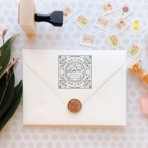 Peut inclure: Une enveloppe blanche avec un tampon à encre noire carré orné d'une bordure florale et du texte The Smiths, 14 Meadow Ln, Cottleville, MO, 63376. Un sceau en cire cuivré avec un motif d'abeille est centré sur le rabat de l'enveloppe.
