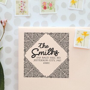 Peut inclure: Une empreinte de tampon à encre noire carrée sur une enveloppe pêche clair, présentant un cadre en losange central rempli de motifs floraux linéaires complexes. Le texte indique : The Smiths, 1712 Bald Hill Rd., Jefferson City, MO, 65101.