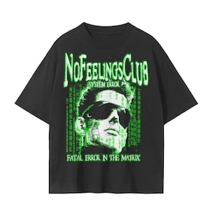 Puede incluir: Una camiseta negra de manga corta con un estampado gráfico de una persona con gafas de sol. El texto dice NOFEELINGSCLUB, SYSTEM ERROR y FATAL ERROR N THE MATRIX, rodeado de patrones de código digital verde sobre fondo negro.