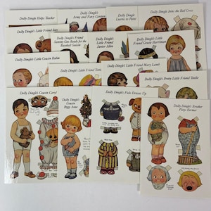 May include: A collection of vintage-style paper doll sheets featuring Dolly Dingle and friends. Each sheet displays illustrated characters with various outfits, accessories, and printed titles such as Dolly Dingle Helps Teacher and Dolly Dingle Joins the Red Cross, arranged in a grid-like layout on white paper.
