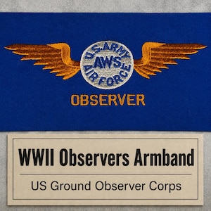 May include: A blue fabric armband featuring an embroidered gold wing emblem centered above a circular patch with the text U.S. ARMY AIR FORCE AWS. The word OBSERVER is embroidered in gold below the emblem. A label reads WWII Observers Armband.