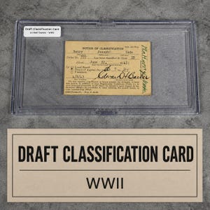 May include: A vintage tan United States WWII Draft Classification Card for Henry Joseph Gade, encased in a clear protective plastic holder. The card features printed text, handwritten details, and a signature, labeled with a white identification tag.