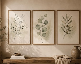 May include: Three framed botanical prints featuring watercolor illustrations of leaves and branches in shades of green and brown. The prints are displayed on a neutral-toned wall above a wooden bench with decorative items.