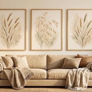 May include: A set of three rectangular wall art prints in light wood frames, each featuring a watercolour illustration of wheat stalks in shades of tan, beige, and soft green against a cream background, displayed above a beige upholstered sofa.