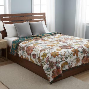 Puede incluir: Una cama con cabecero de madera y un edredón con estampado floral. El edredón presenta un fondo blanco con grandes flores naranjas, amarillas y burdeos. Hay dos almohadas grises y dos almohadas blancas en la cama. El edredón tiene un borde verde oscuro.