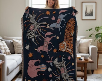 May include: A navy blue throw blanket featuring a whimsical circus design. The blanket showcases illustrations of zebras, horses, an elephant, and a tiger, with star and firework accents. The blanket has a fringed edge.