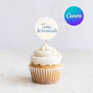 Könnte beinhalten: Ein Cupcake mit weißem Zuckerguss und einem runden Topper mit der Aufschrift "Team Jeremiah" in blauer Schrift. Der Topper befindet sich auf einem Holzstab. Ein Canva-Logo ist im Hintergrund.