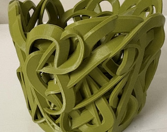 May include: A 3D-printed, olive-green decorative bowl with an intricate, interwoven design. The openwork pattern creates a visually interesting texture, suitable for holding small items or as a standalone art piece. The bowl's form is round with a slightly flared top.